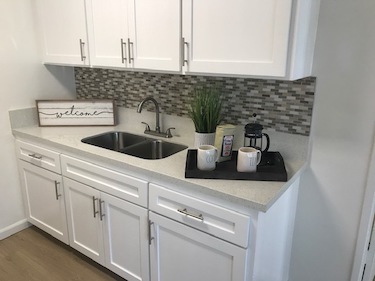 Kitchen with white cabinets, gray granite counter and tile splash.