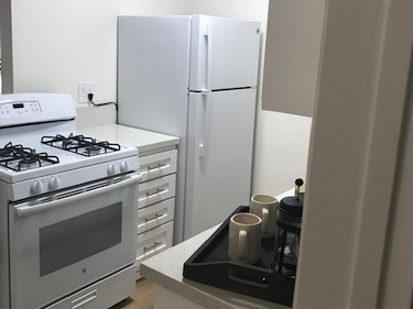 Looking into the kitchen. Stove, oven and large fridge.